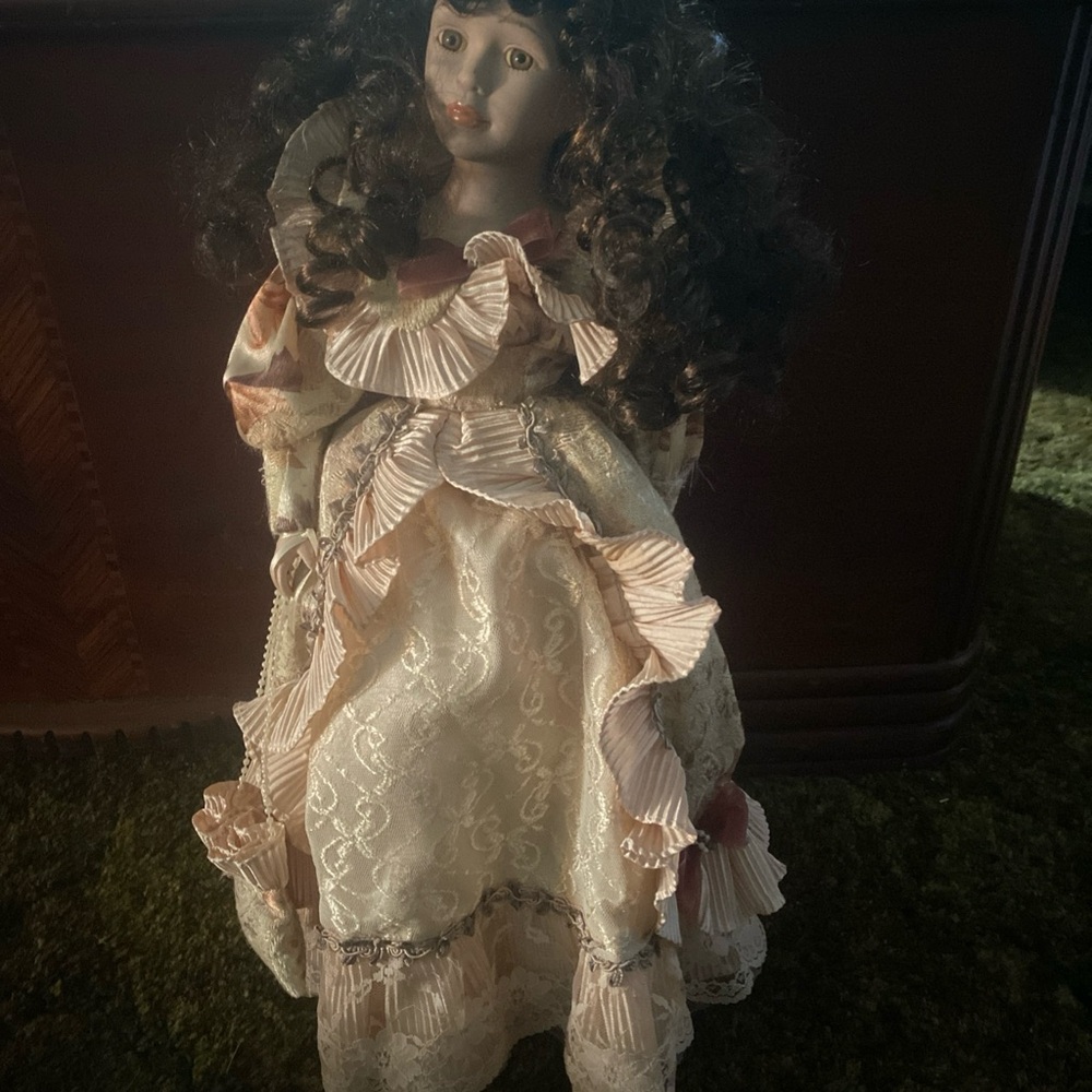 Porcelain doll with black curly hair and cream colored dress